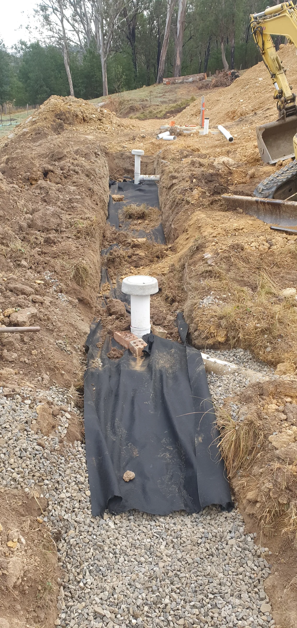 A drainage trench with inspection riser during a septic system installation