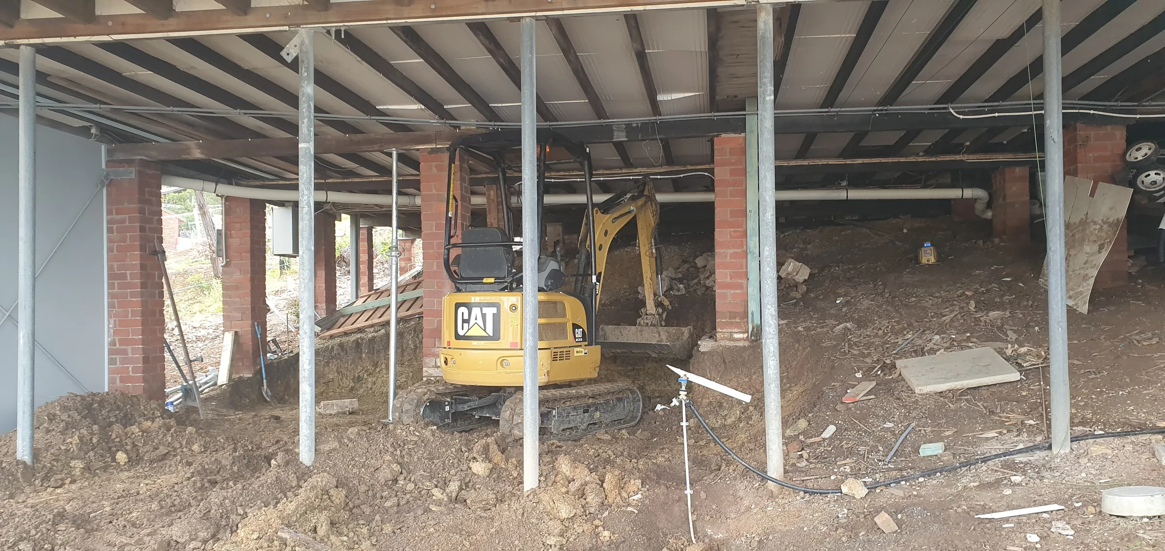 A house being underpinned with a mini excavator working underneath